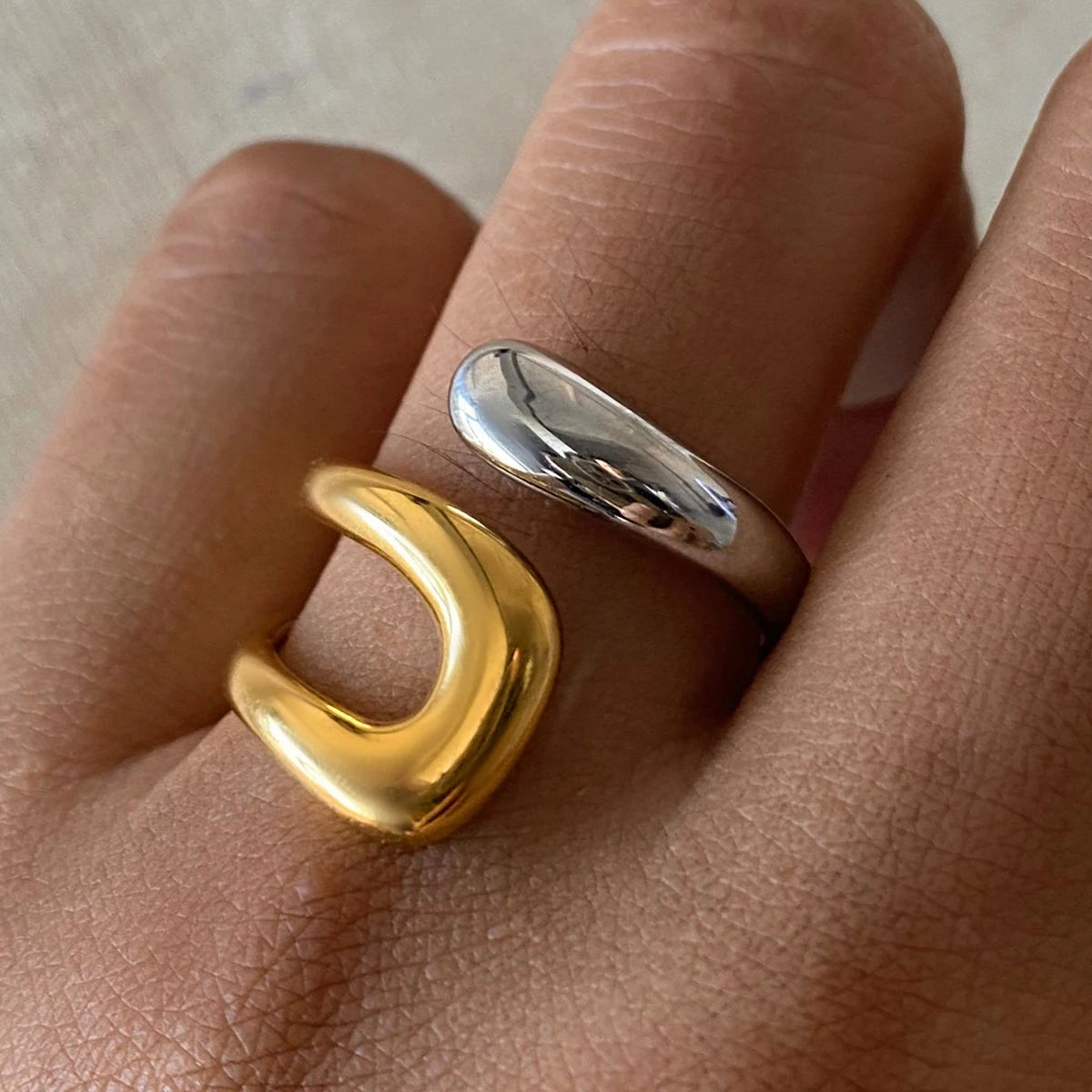 An 18K gold asymmetric open ring worn on a person's finger, with one side gold-colored and the other silver-colored.