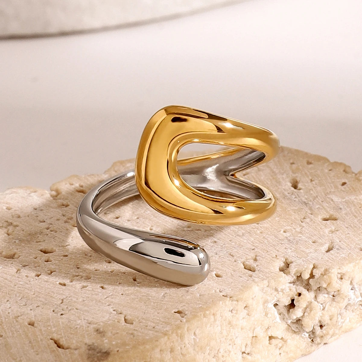 An 18K gold asymmetric open ring worn on a person's finger, with one side gold-colored and the other silver-colored.