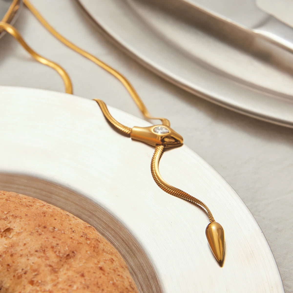 Gold necklace with a diamond on a white plate