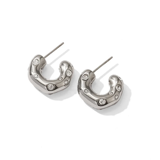 A pair of silver-colored hoop earrings with sparkling zircon inlays, displayed against a white background.